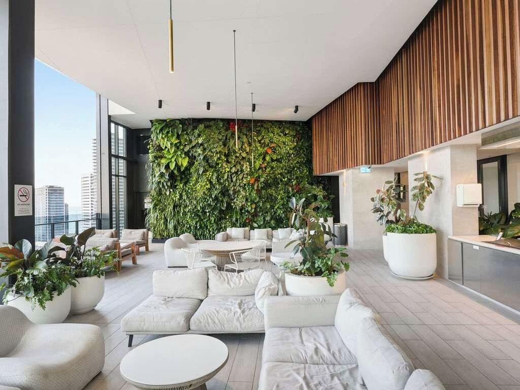 Un espacio interior moderno con una zona de estar, un jardín vertical y un mostrador de recepción.