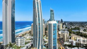 A high-rise hotel with a curved facade, located near a beach and a cityscape. - Hilton Surfers | Vogue on Orchid | 2BR Ocean View (Surfers Paradise)