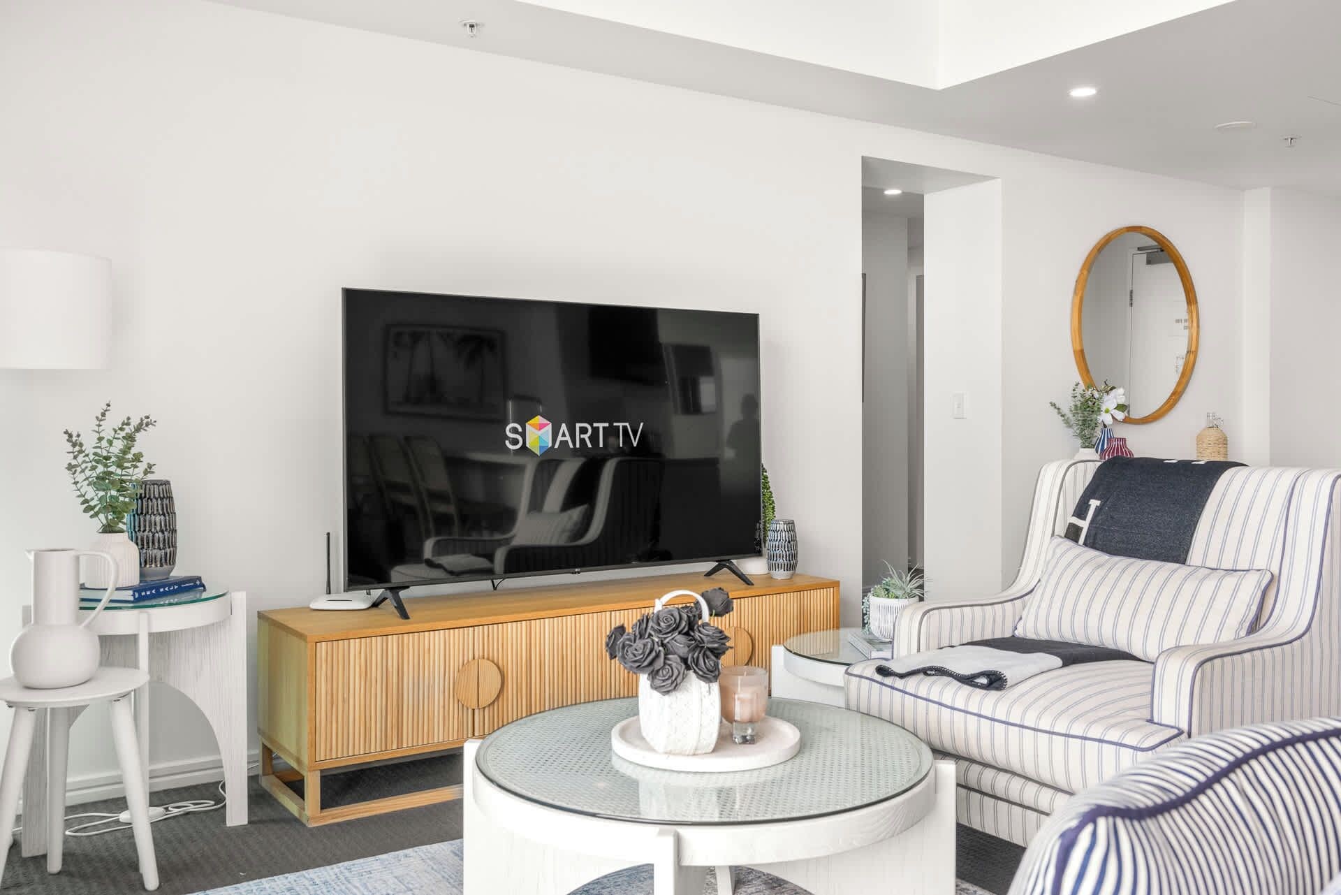 A modern living room with a flat-screen TV, a sofa, a coffee table, and a side table.