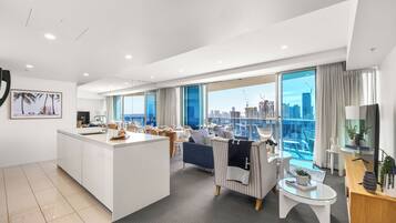 Una habitación de hotel moderna con un balcón grande, un área de comedor y vistas del horizonte de la ciudad.