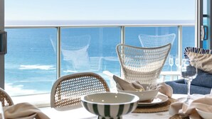 A dining area with a view of the ocean, featuring wicker chairs and a table set for two. - Hilton Surfers | Vogue on Orchid | 2BR Ocean View (Surfers Paradise)