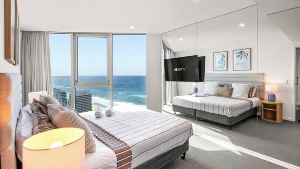 A modern hotel room with a large bed, a TV, and a view of the ocean. - Hilton Surfers | Vogue on Orchid | 2BR Ocean View (Surfers Paradise)