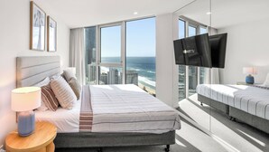 A hotel room with a large window, a bed, a TV, and a bedside table. - Hilton Surfers | Vogue on Orchid | 2BR Ocean View (Surfers Paradise)