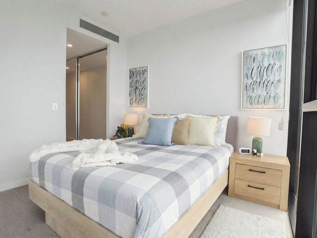 A bedroom with a bed, bedside tables, and artwork on the walls.