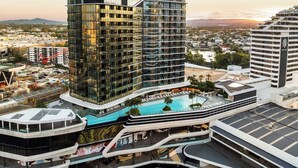 A high-rise hotel with a modern glass facade, a rooftop pool, and a view of the surrounding cityscape. - Broadbeach 2BR | Atelier 35, Casino Towers (Broadbeach)