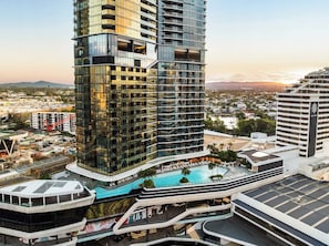 A high-rise hotel with a modern glass facade, a rooftop pool, and a view of the surrounding cityscape. - Broadbeach 2BR | Atelier 35, Casino Towers (Broadbeach)