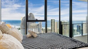 A high-rise hotel room with a large window offering a view of the city skyline and the ocean. - Broadbeach 2BR | Atelier 35, Casino Towers (Broadbeach)