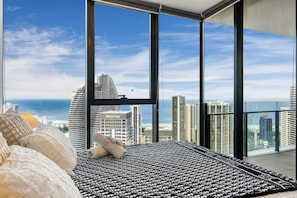 A high-rise hotel room with a large window offering a view of the city skyline and the ocean. - Broadbeach 2BR | Atelier 35, Casino Towers (Broadbeach)