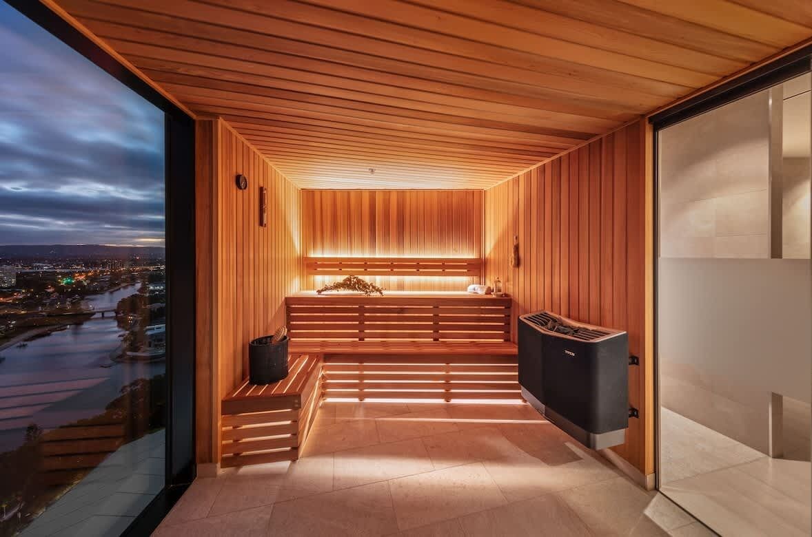 A modern sauna room with wooden walls, a bench, and a sauna unit.