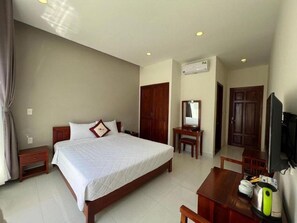 A hotel room with a large bed, a desk, a chair, a television, and a wardrobe. - Vanda Hotel (Phu Quoc)
