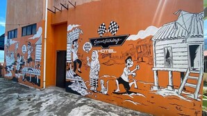 Um mural em um edifício com a placa de um hotel, retratando uma cena de pesca esportiva com pessoas e um barco.