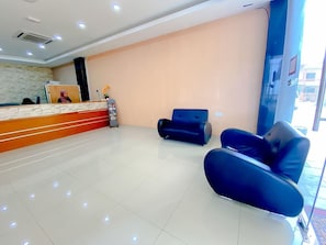 Una zona de recepció amb mostrador, una cadira de cuir negre i una finestra gran.