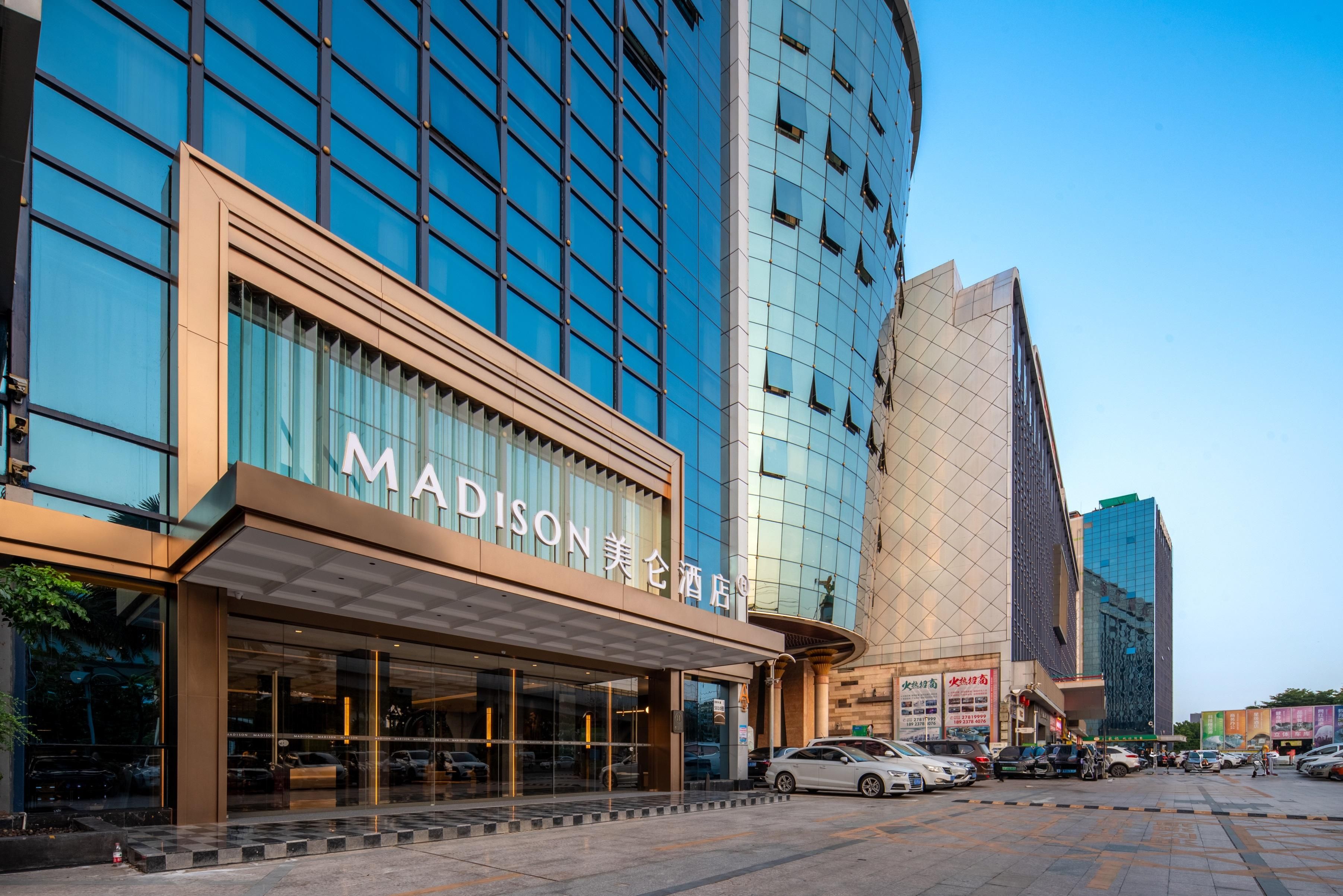 Un hôtel moderne doté d’une façade en verre et d’une enseigne bien visible indiquant « MADISON HOTEL ».