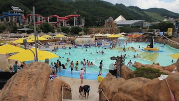 A water park with multiple pools, slides, and a large rock formation in the foreground.