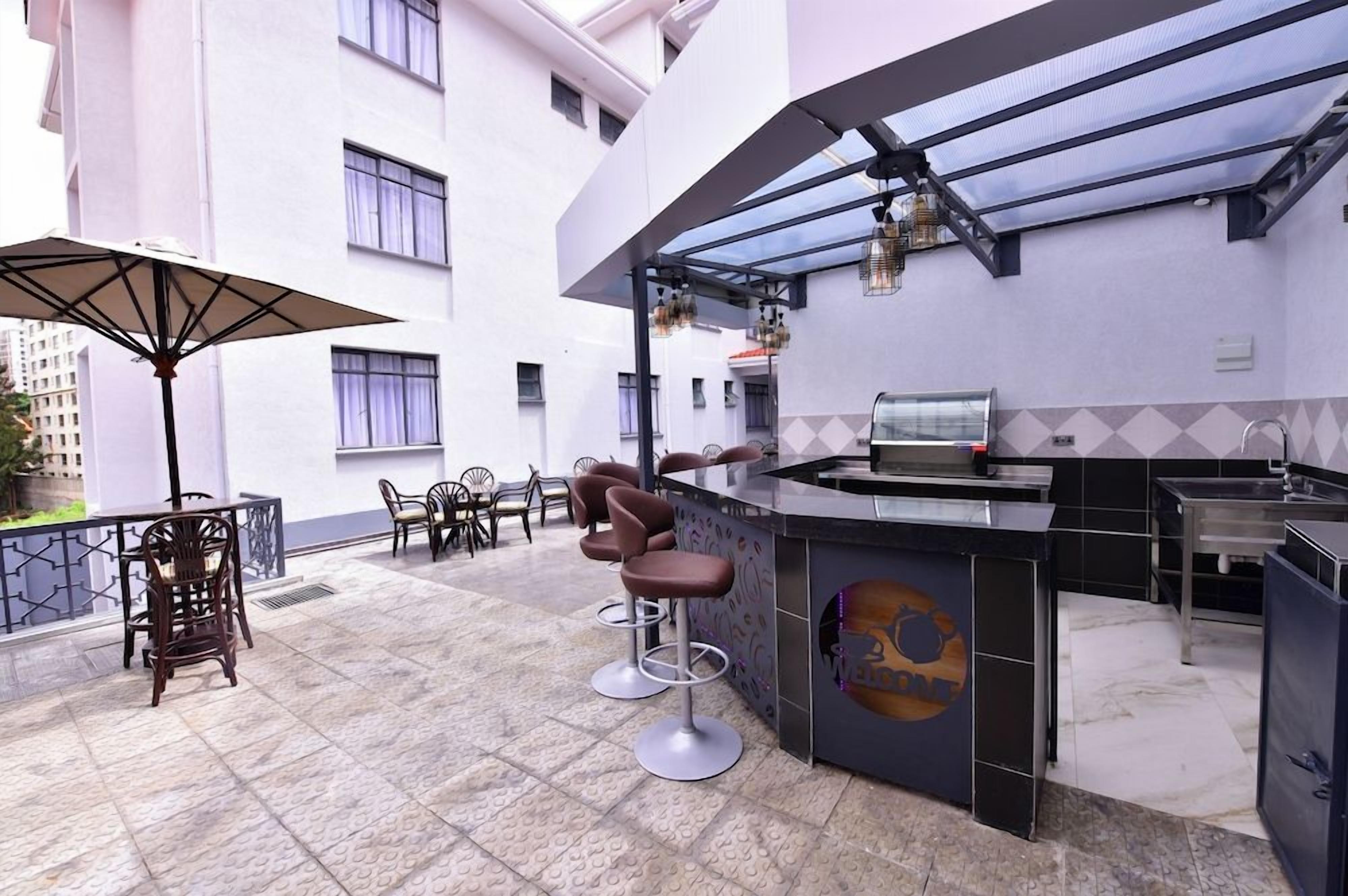 Un área de bar al aire libre con mostrador, taburetes y cerramiento de vidrio.