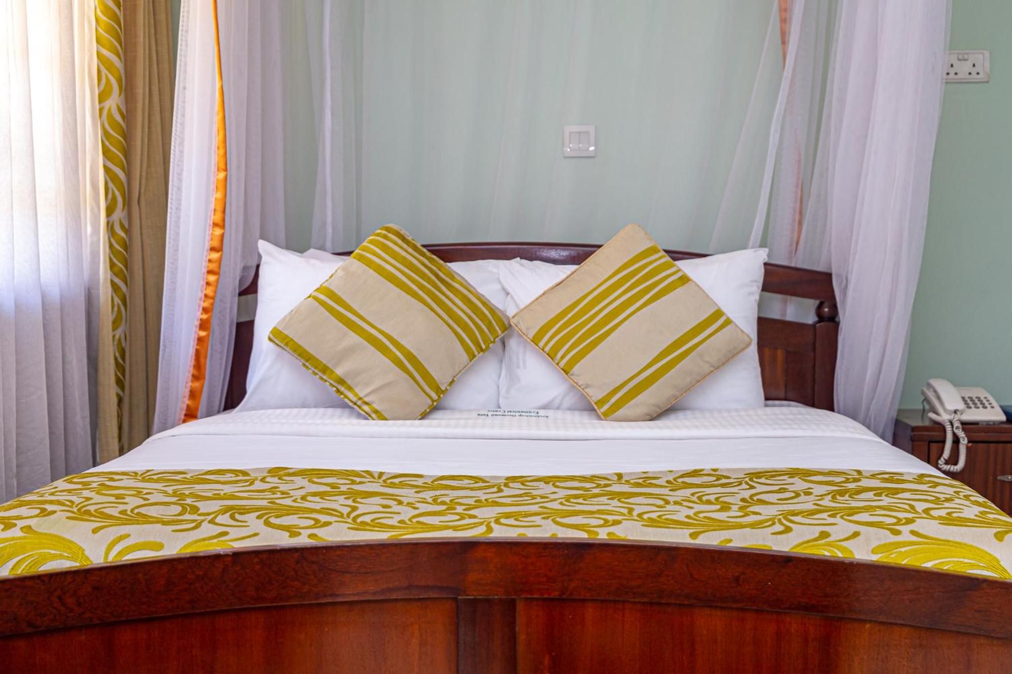 A bed with a wooden headboard, white bedding, and two pillows with a striped pattern.