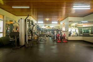 Un gimnasio con diferentes máquinas de ejercicio, un espejo grande en la pared y techo de madera.