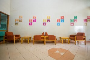 A waiting area with a tiled floor, wooden furniture, and a wall displaying various UN Sustainable Development Goals. - Desmond Tutu Guest House (Nairobi)