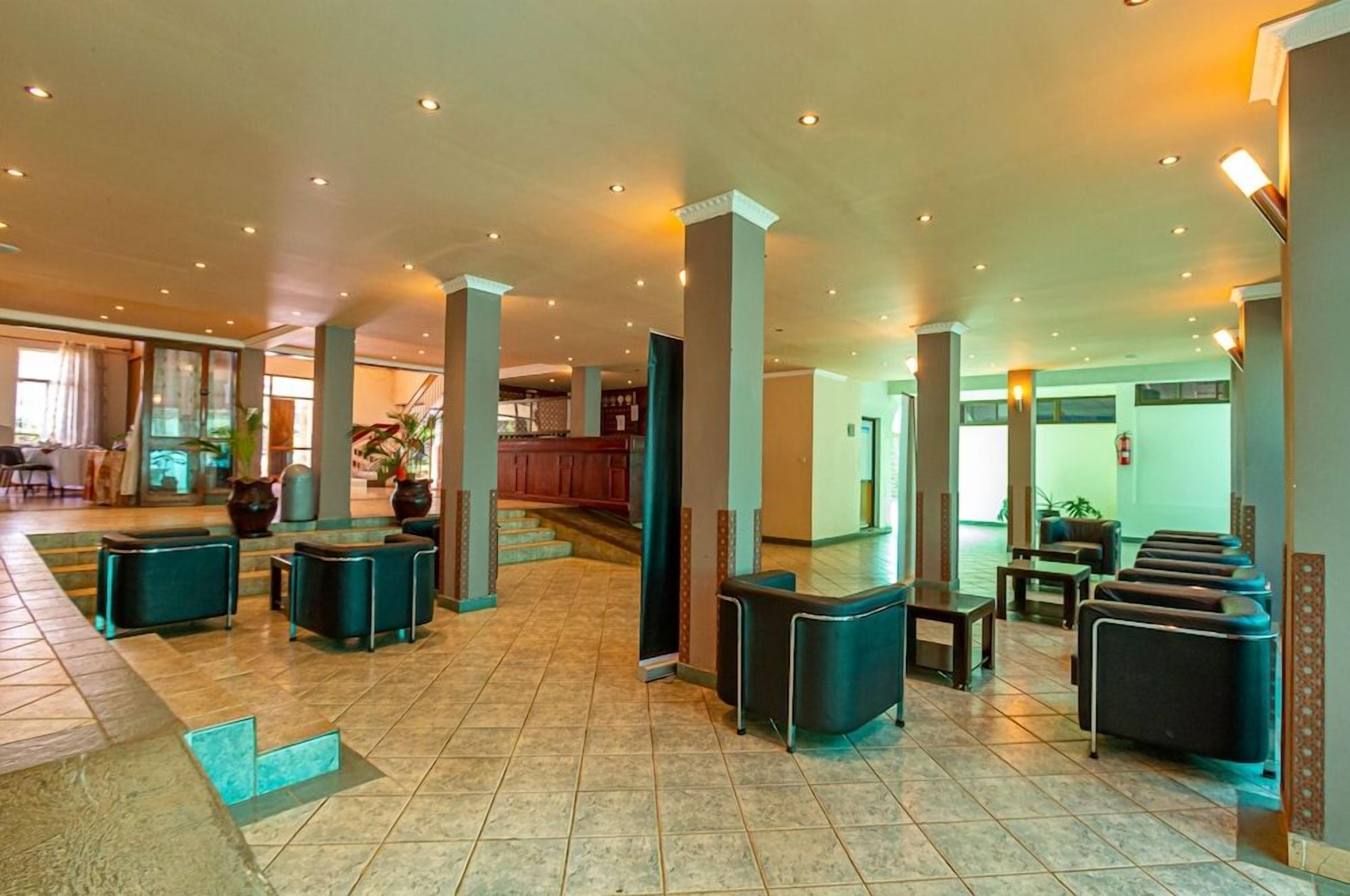 A spacious lobby with a high ceiling, multiple seating areas, and a staircase leading to upper floors.
