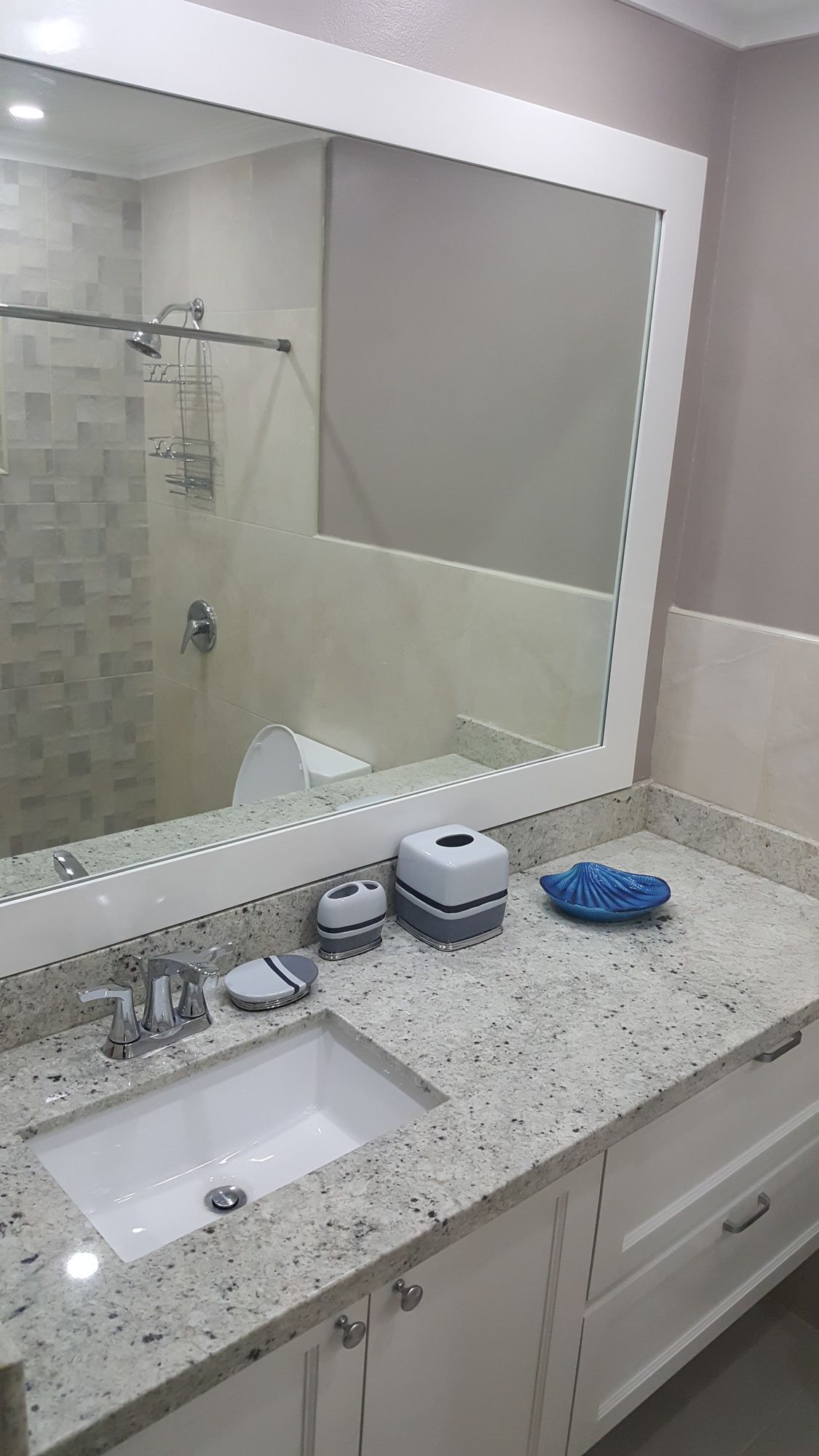 Une salle de bain avec un grand miroir, un lavabo, une douche et un porte-serviettes.