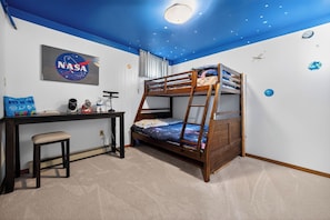 A bunk bed with a starry ceiling, a desk with a computer, and a NASA poster.
