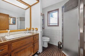 A bathroom with a wooden vanity, a sink, a toilet, and a shower. - Cozy 3-bedroom bed & breakfast in charming Jefferson with AC (Jefferson)