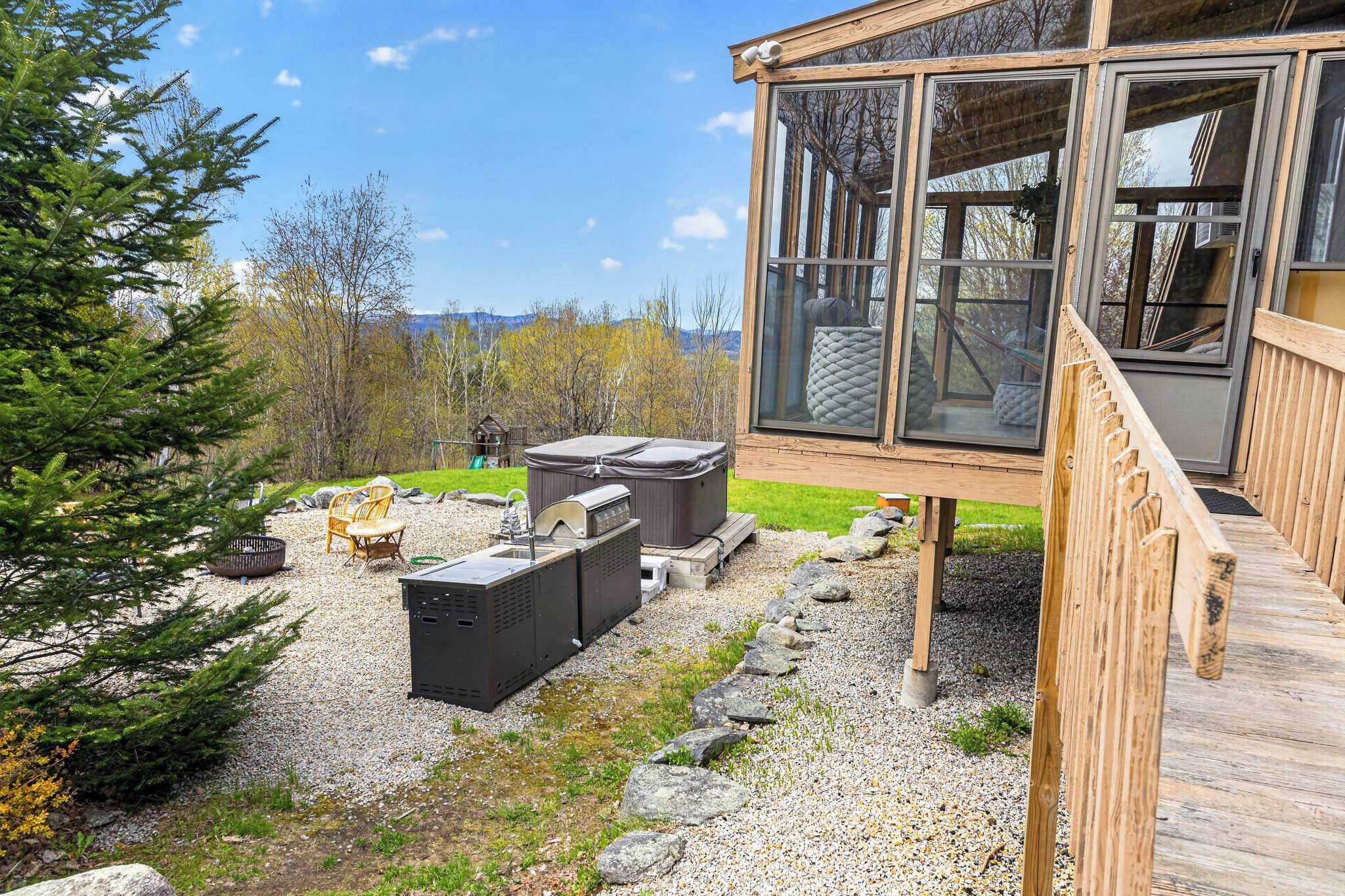 A modern cabin with a deck, outdoor seating, and a hot tub.