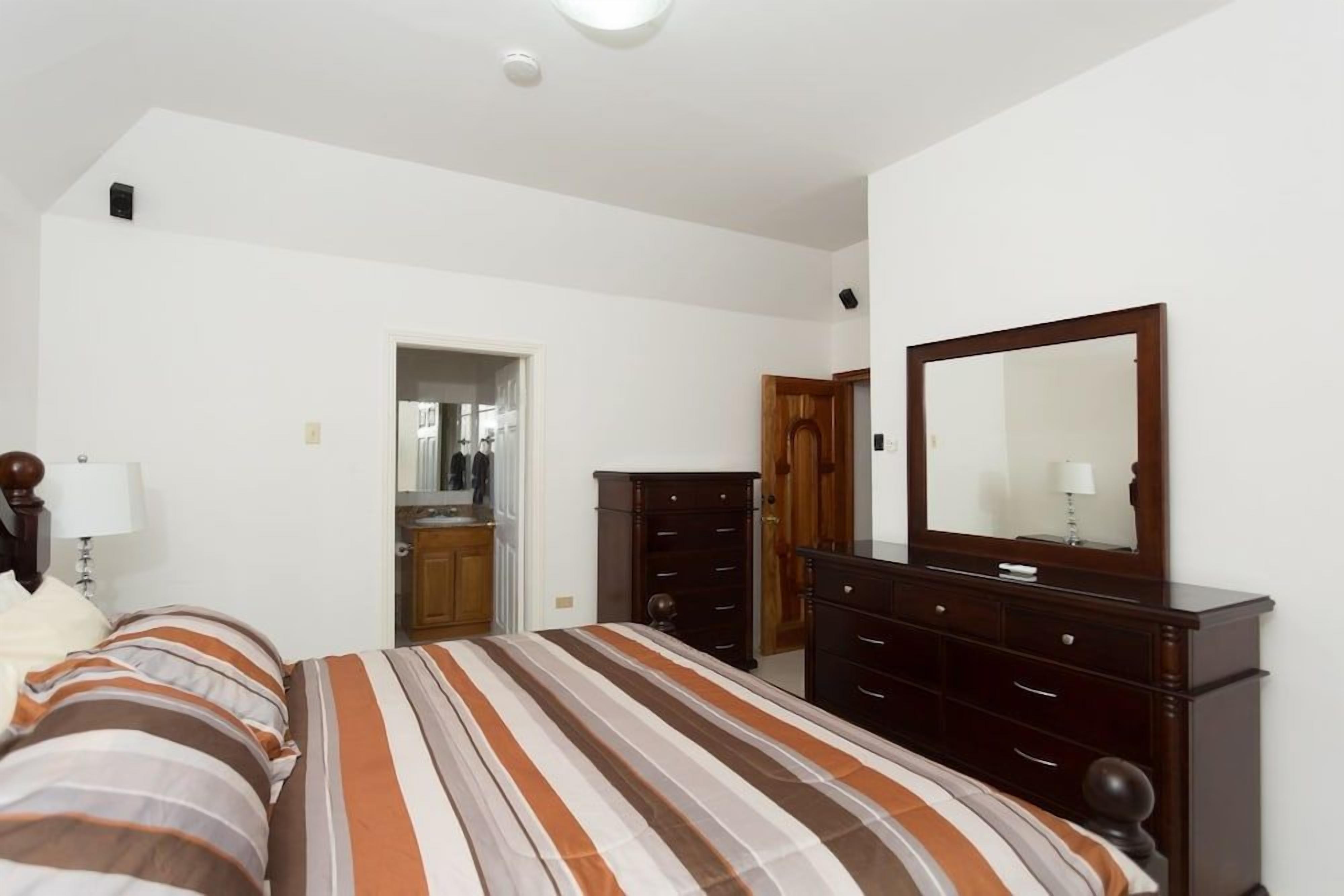 A bedroom with a bed, dresser, and mirror.