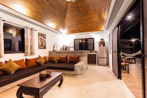 A modern living room with a sofa, coffee table, and a dining area with a hammock. - Koh Tao Heights Pool Villas (Koh Tao)