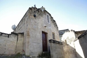 Un edificio in pietra con una sola porta e una piccola finestra, circondato da mura.