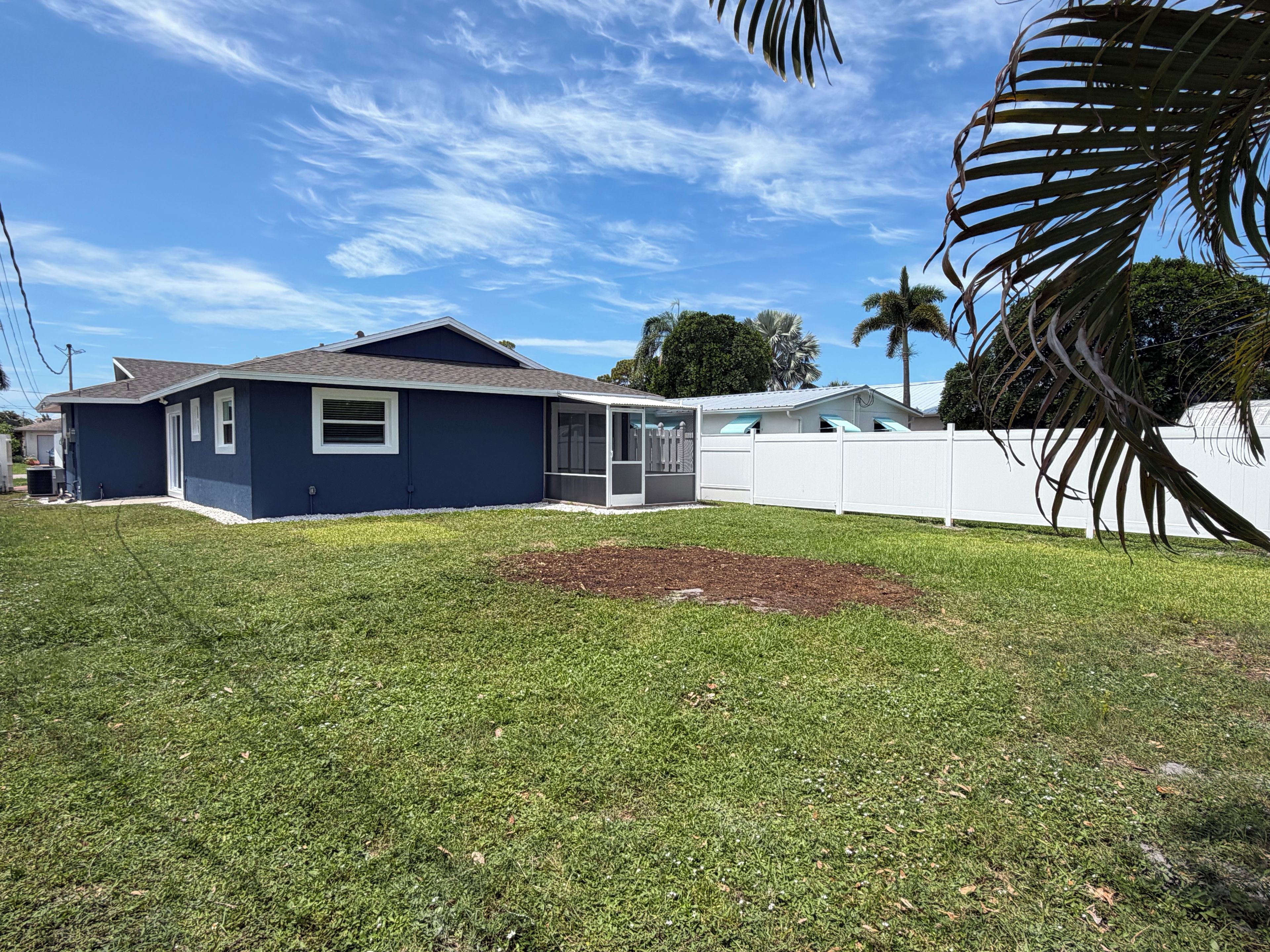 A residential property with a blue house, a white fence, and a well-maintained lawn.