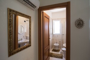 Un pasillo que conduce a un baño con espejo, lavamanos e inodoro.
