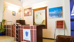 A reception area with a reception desk, a staircase, a wall-mounted sign, and a framed picture. - Fabhotel The Residency DLF Galleria (Gurugram)