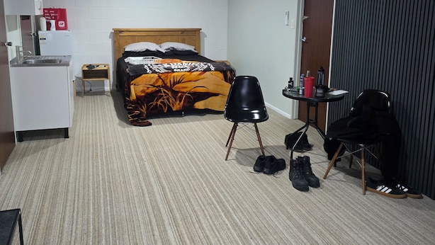 Ein Hotelzimmer mit einem Bett, einem kleinen Tisch, einem Sessel, einem Schreibtisch und einer Küchenzeile.