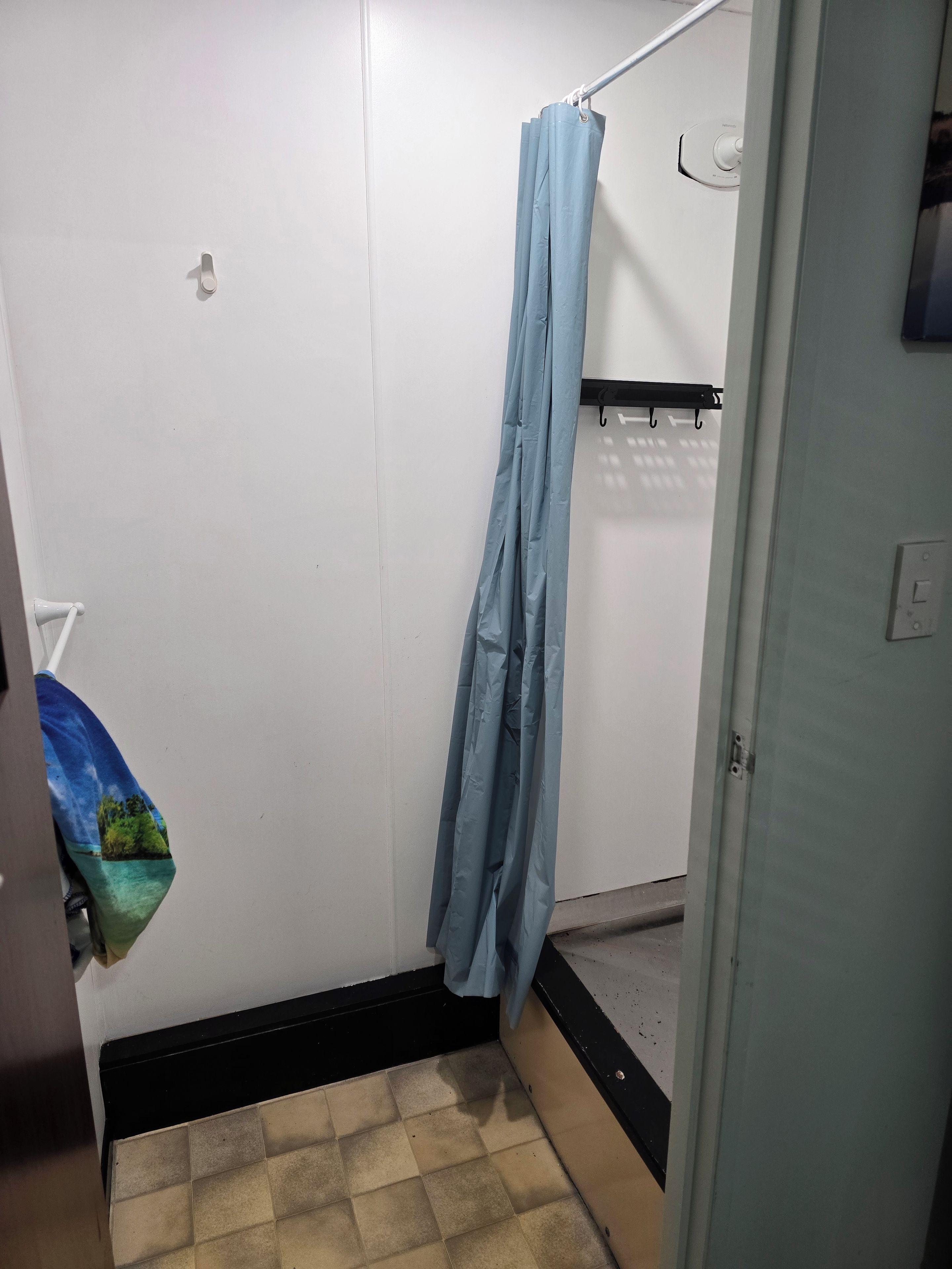 Un baño pequeño con cortina de ducha, toallero y un inodoro.