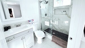 A modern bathroom with a glass-enclosed shower, a white sink, and a toilet. - Cozy 1-bedroom & 2beds house in Rowland Heights with AC near Disneyland Park (Rowland Heights)