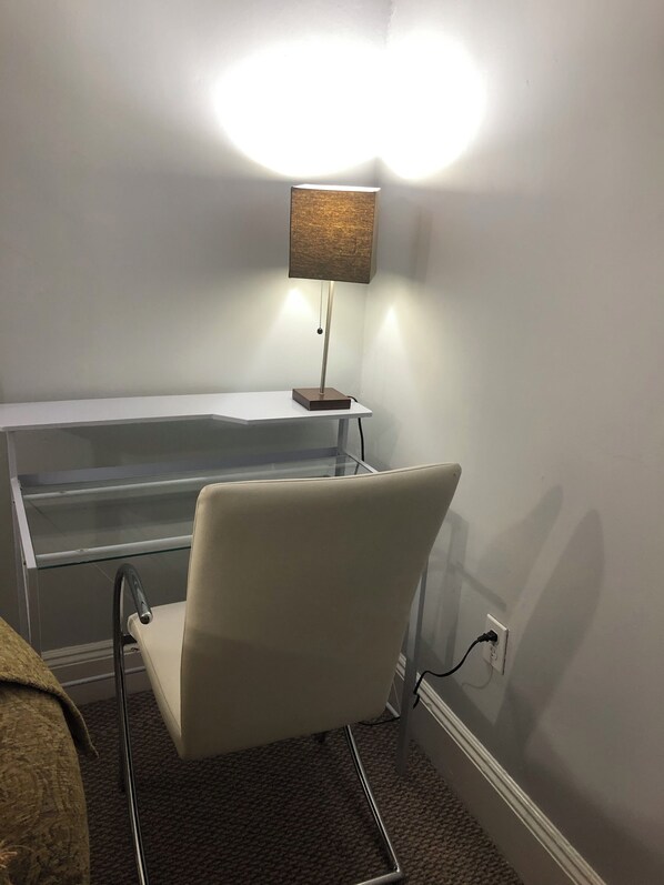 A room with a white chair, a glass-top table, and a floor lamp.