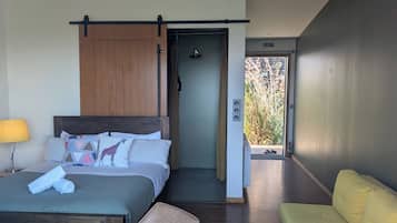 Ett modernt hotellrum med en säng, en stol, en soffa och ett badrum med dusch.