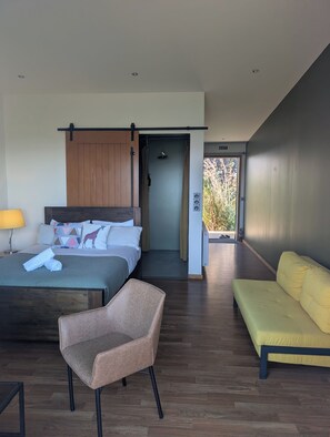 Una habitación de hotel moderna con una cama, una silla, un sofá y un baño con ducha.