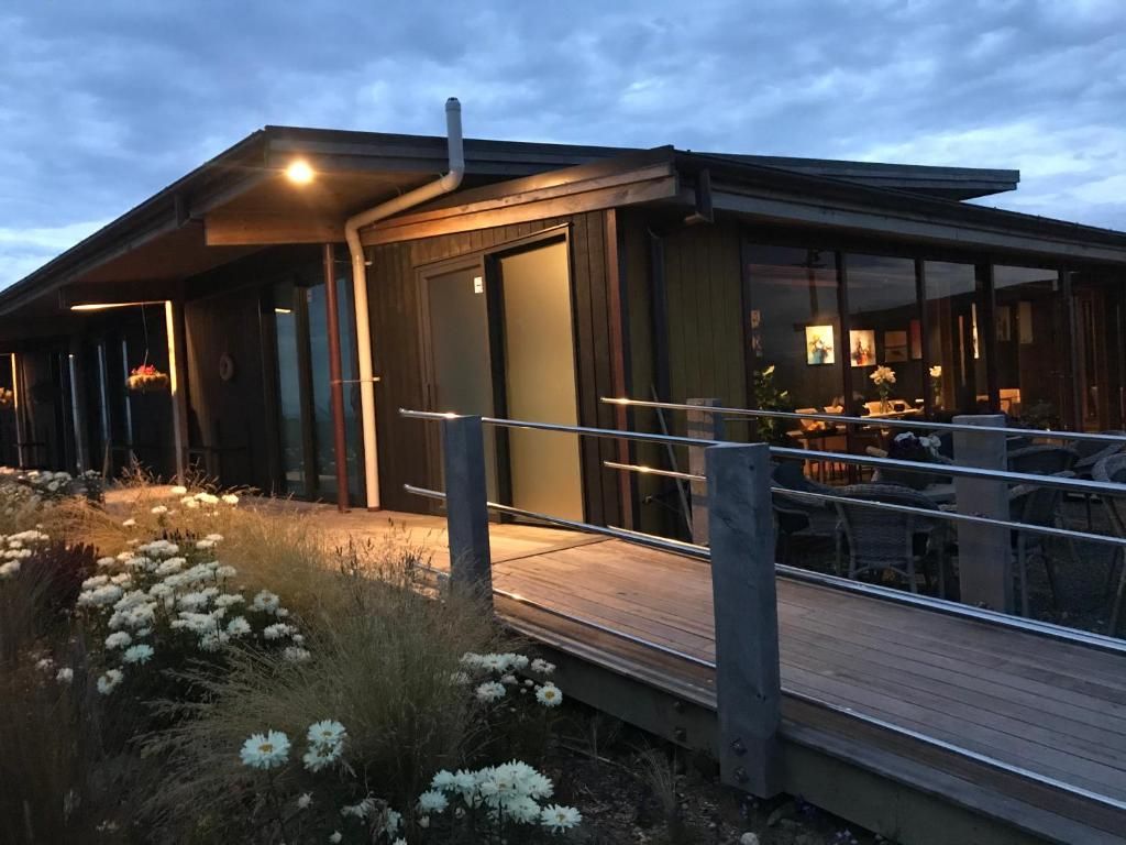 A modern building with a covered outdoor area, a wooden deck, and a glass entrance.
