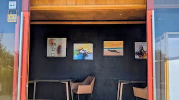 An entrance with a wooden ceiling, black walls, and a black floor. There are two chairs and a small table.