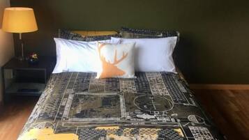 A bed with a patterned bedspread, a pillow with a tree design, and a bedside lamp.