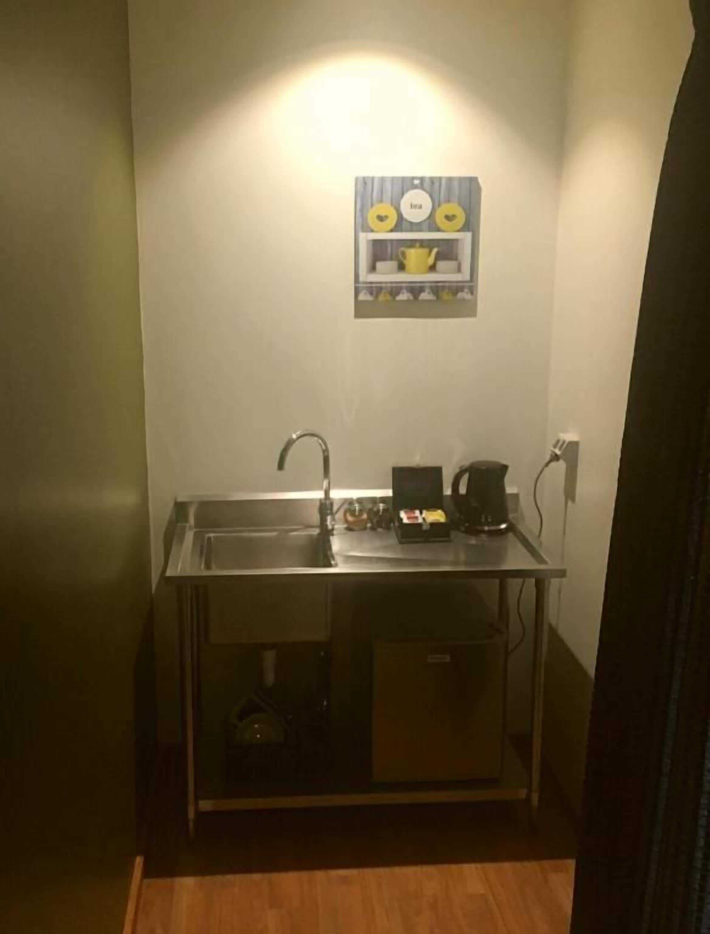 A compact kitchenette with a sink, a coffee maker, and a small cabinet.