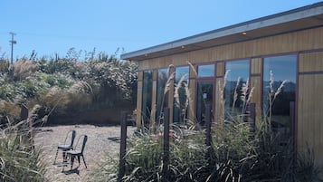 A building with large windows, surrounded by gravel and tall grasses.