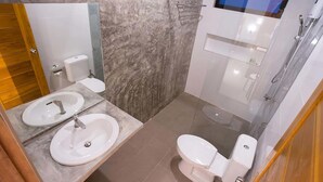 A modern bathroom with two sinks, a toilet, and a shower.