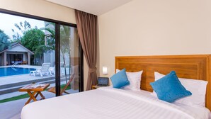 A hotel room with a bed, a laptop on a bedside table, and a view of an outdoor swimming pool.