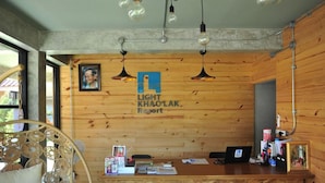 A reception desk with a wooden wall, a framed picture, and a sign that reads 'LIGHT KHAO LAK Resort.'