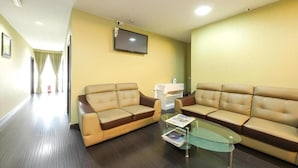 A hotel lobby with two sofas, a glass coffee table, a television mounted on the wall, and a trash bin. - Capital O 812 Hotel SMC Seksyen 13 (Shah Alam)