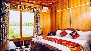 Quarto de madeira com cama, cortinas e vista para o verde.