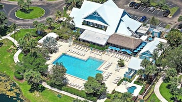 A resort with a large pool, lounge areas, and a tennis court.